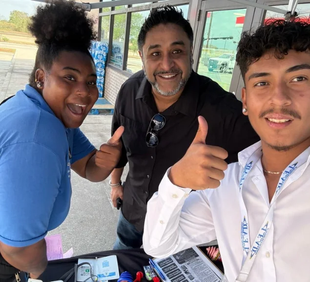 Three GA Jersey Village team members at an outreach table under a canopy