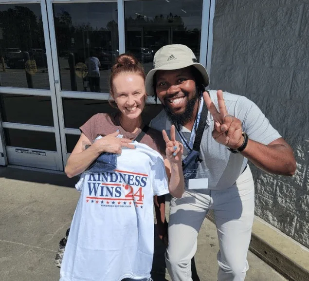 Two people smiling with a Kindness Wins 24 anti-bullying campaign shirt during community outreach